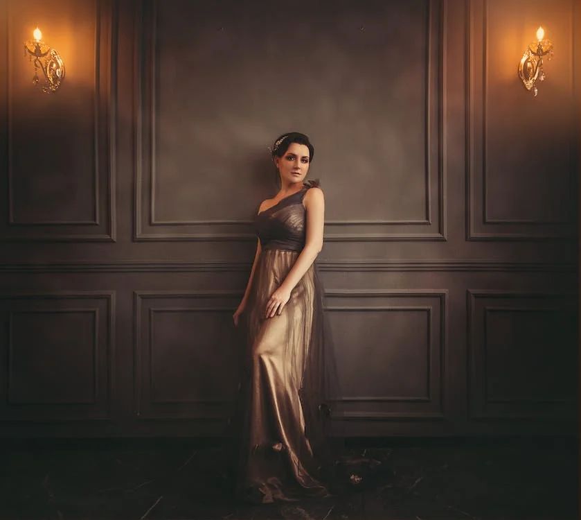 image showing a woman in an evening gown, leaning against a wall