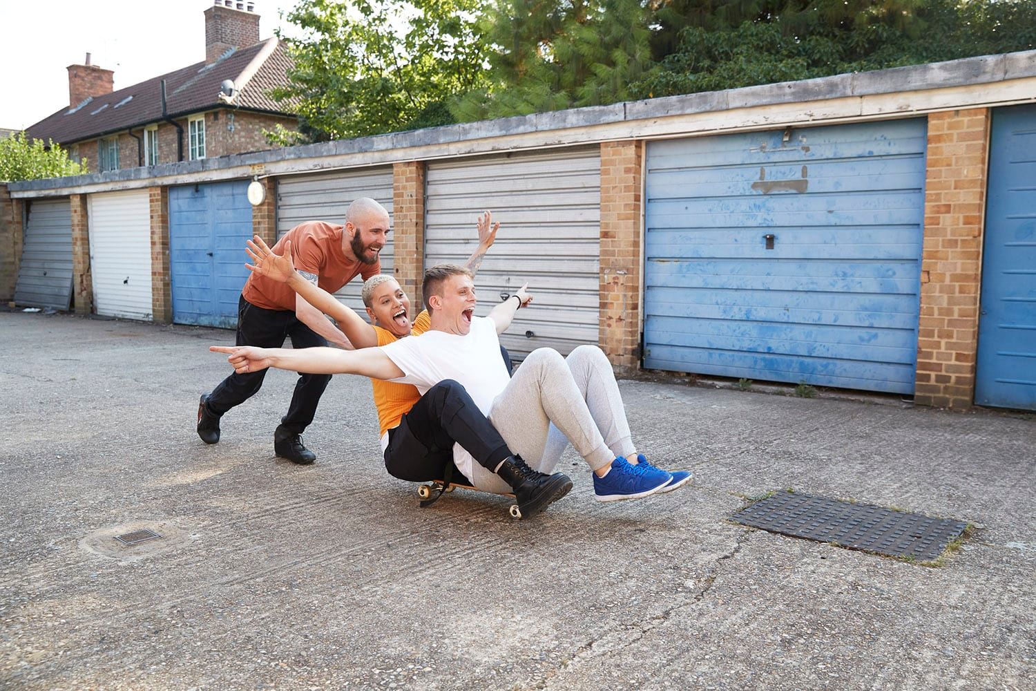 image of a man pushing two friends of a skateboard, taken by a London lifestyle photographer by Pete Muller