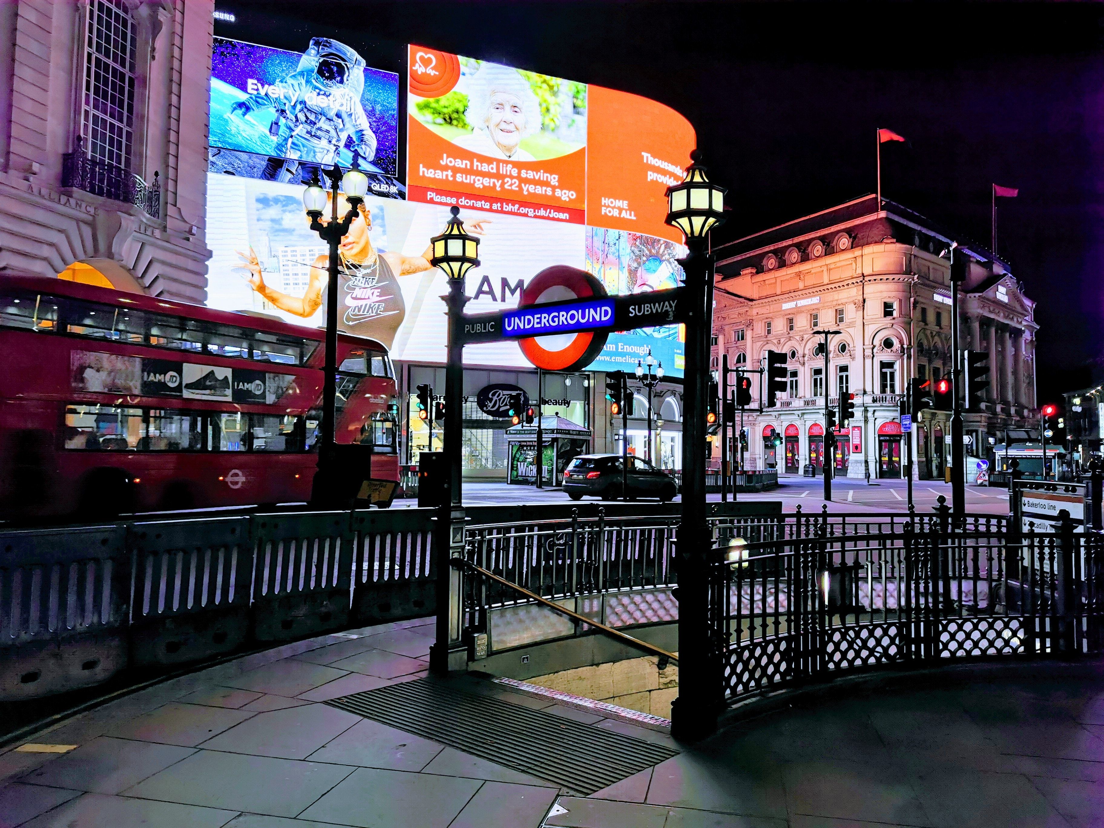 image of Piccadilly circus at night with large illuminated billboards in the background