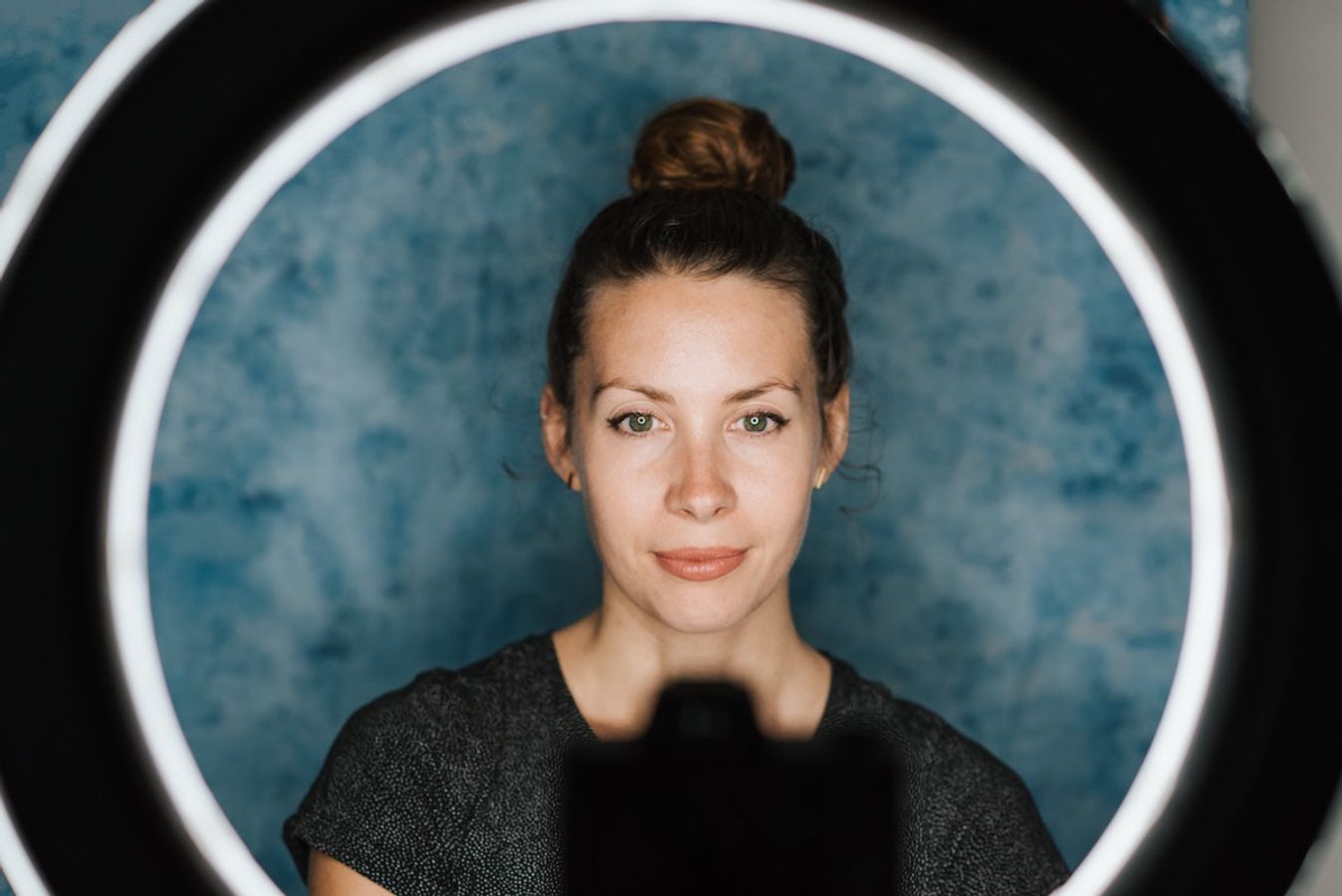 woman standing in front of camera and ring light in a studio