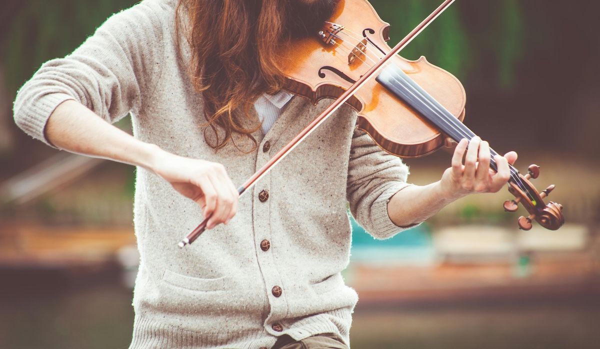 a woman playing violin outdoors