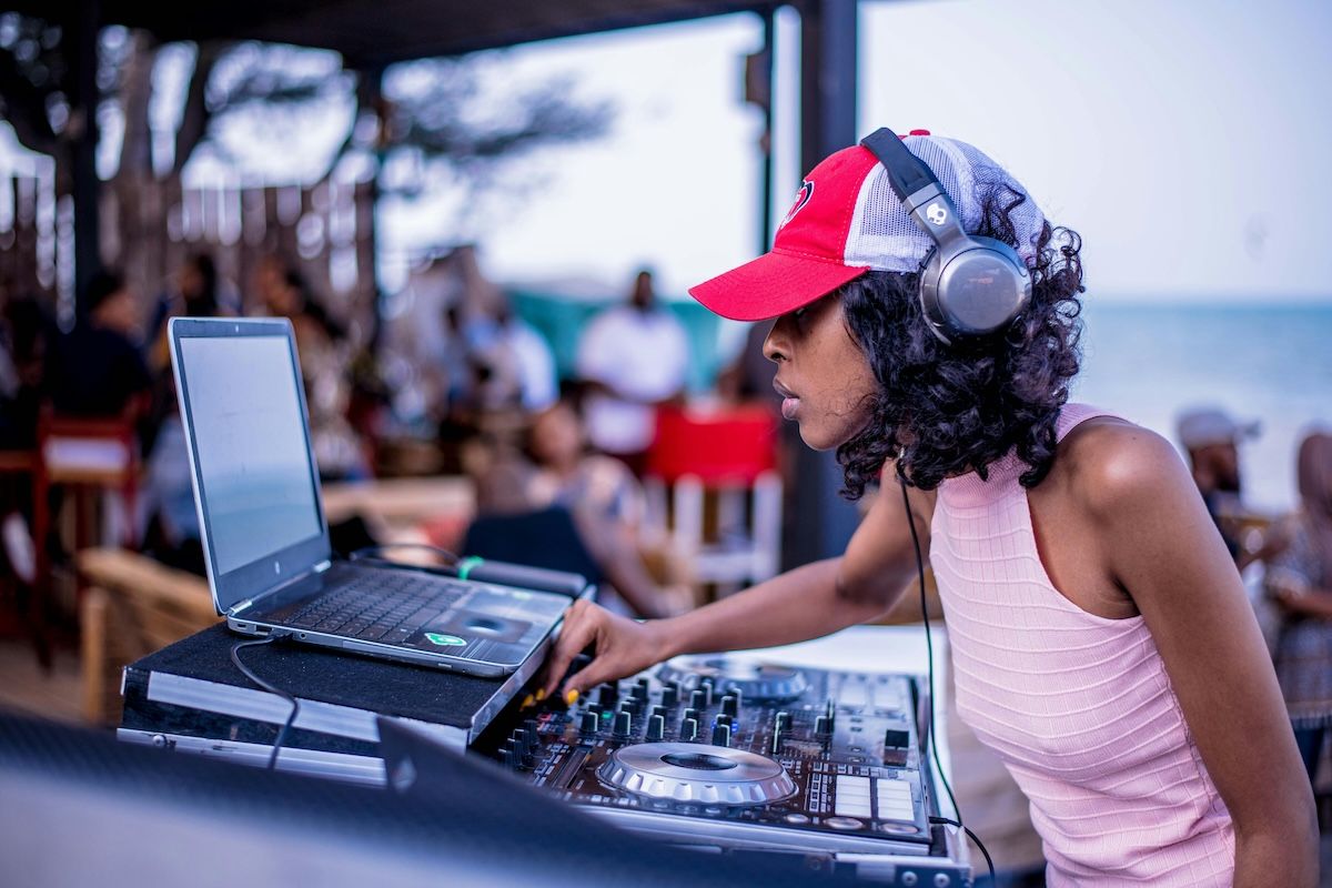 Female DJ performing a set outdoors with decks and a laptop