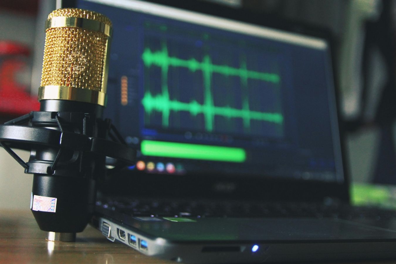 gold condenser microphone in front of a laptop screen